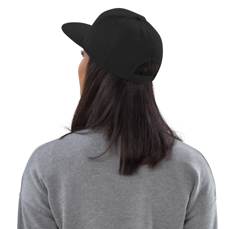Rear view of a woman wearing a black snapback hat to demonstrate the hat's closure and fit.