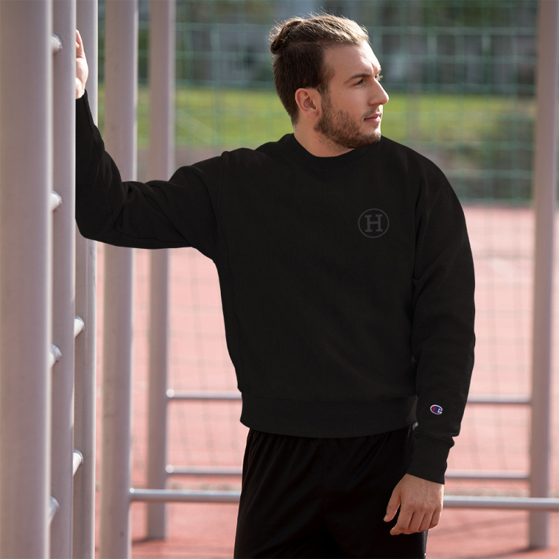 A young man standing by metal railings wearing a black champion sweatshirt with the logo for certified-haters.com printed on the left chest.