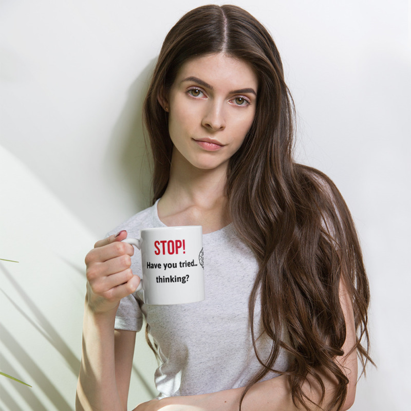 A woman holding a funny mug that says "STOP! Have you tried thinking?"